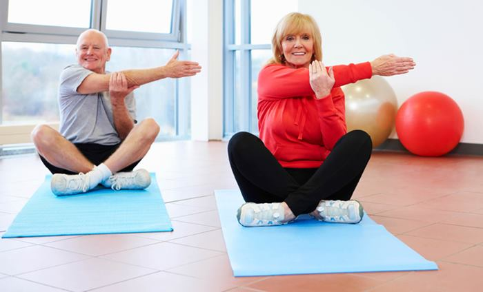 MoveWell coach exercising together with two older adults in a seated mobility class